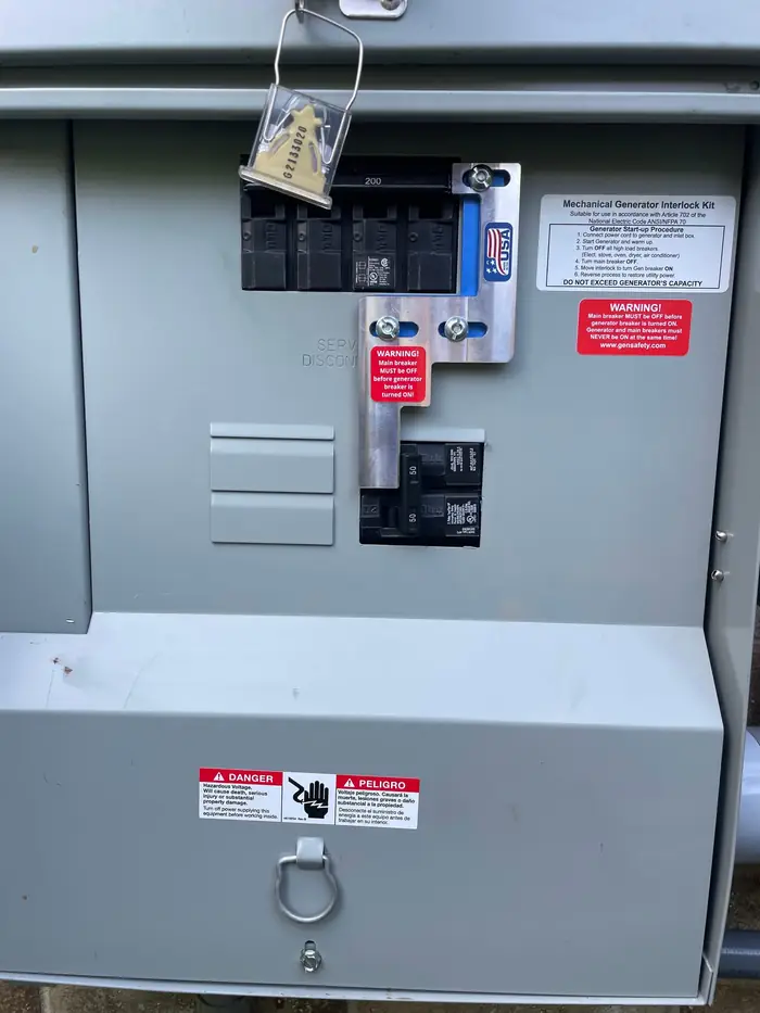 Mechanical generator interlock kit fitted over the main breaker of a 200 amp service disconnect