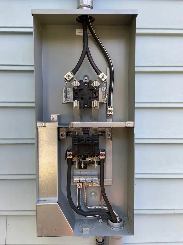 Meter base and main disconnect with the cover off and the service conductors landed on the lugs