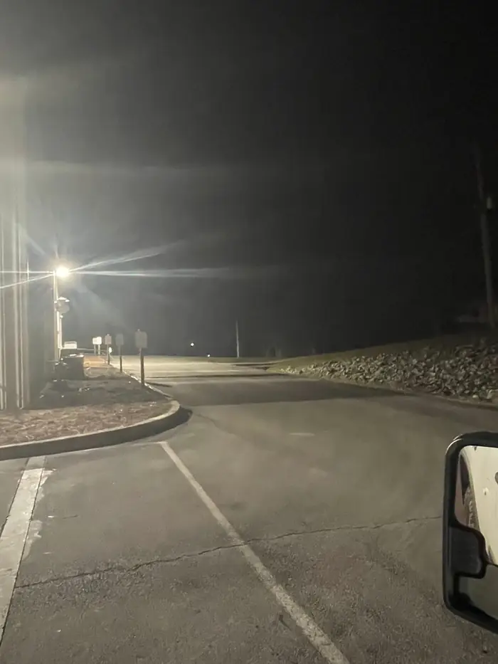 Parking lot pole light lit at night over the drive of a commercial building